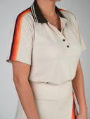 Loma Golf Polo - Tan: A retro-inspired women's golf polo featuring bold, multicolor stripe details on the sleeves and a sleek tan fabric. Perfect for comfort and style on the course.