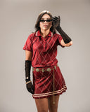 A woman models the Sicilia Skirt in maroon, a stylish golf skirt with a diamond pattern, paired with a matching top. The skirt is lightweight and perfect for active wear, featuring subtle gold accents and a sleek design.