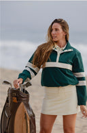 women in green windbreaker and cream skirt 