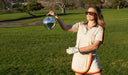 Person holding a disco ball on a grassy field
